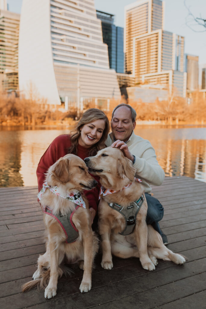 couple with their two golden retrievers in front of the Austin skyline
