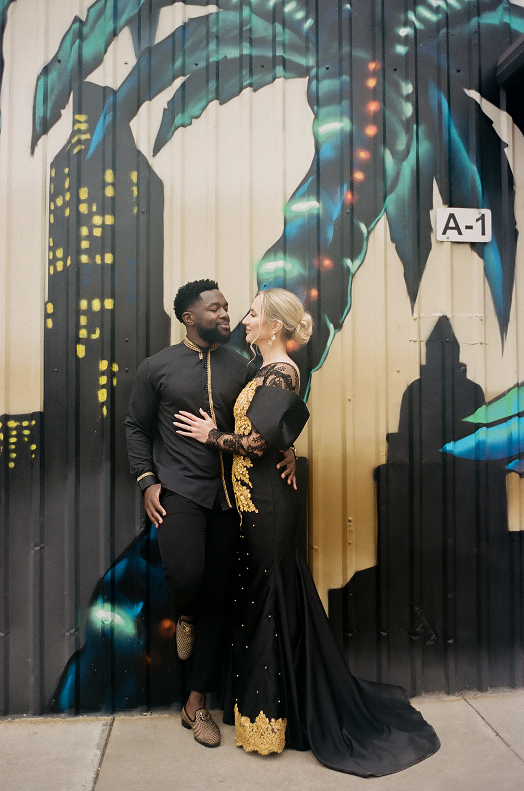 Couple poses for photos in front of the mural outside the Austin Winery