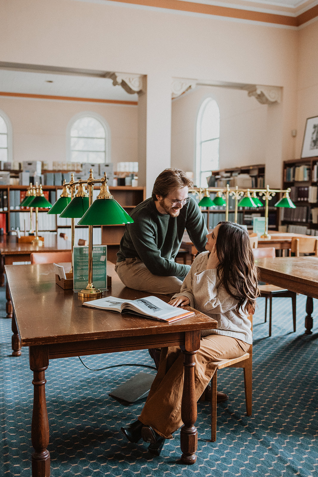 couple sitting inside a library posing for engagement photos