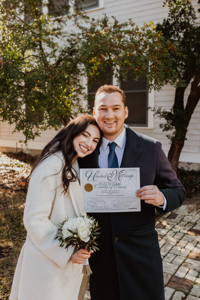 Couple poses with marriage license during courthouse ceremony